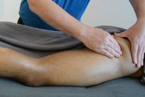 Een masseur kneedt de bilspieren van een massageklant