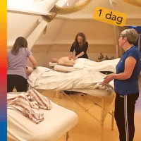 Mensen zijn aan het masseren en de trainer legt iets uit aan een cursist.