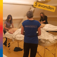 Mensen zijn aan het masseren en de trainer legt iets uit aan een cursist.