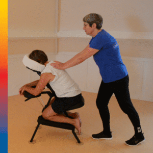 Een masseur geeft een stoelmassage op de rug bij een vrouw die in een stoelmassagestoel zit.